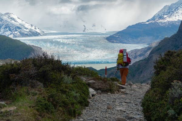 persona che cammina con il ghiacciaio grigio davanti a sé