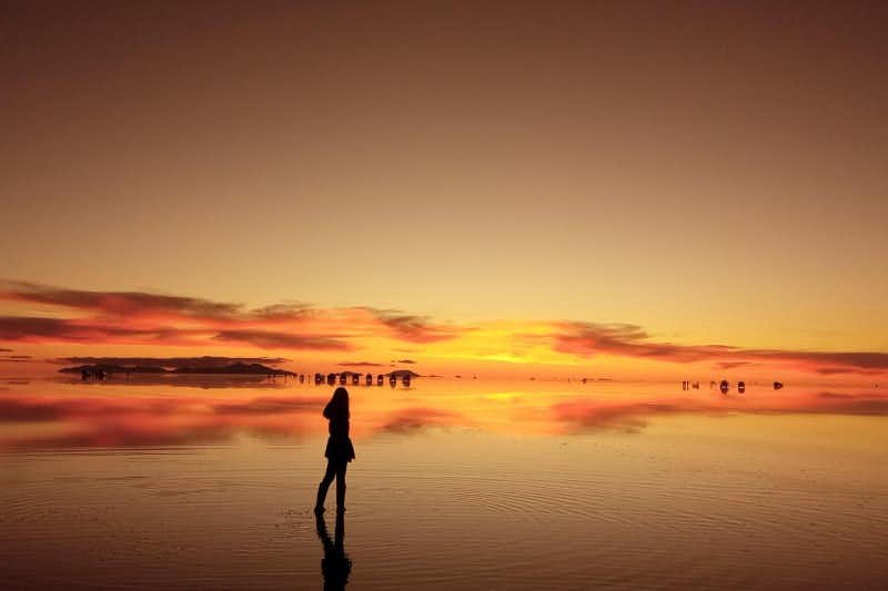 garota no lago de sal de uyuni assistindo ao pôr do sol