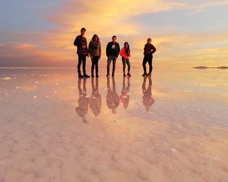 Amigos do nascer do sol em Uyuni tirando fotos com efeito de espelho