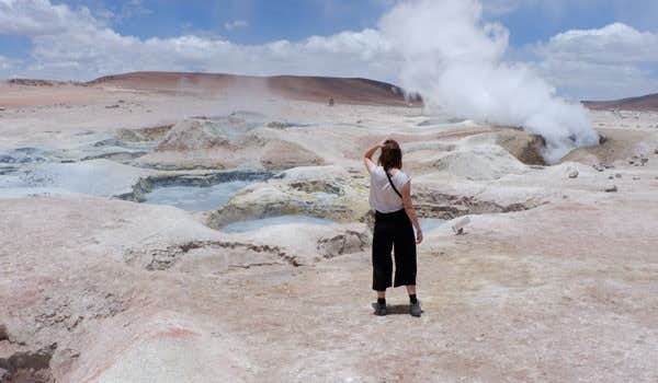 Turista em Geyser Sol de la Mañana com lava vulcânica