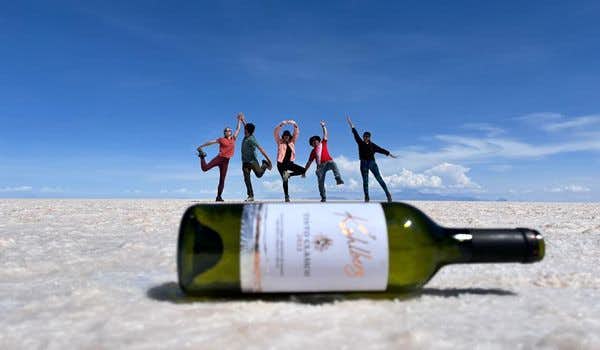 foto engraçada de 5 pessoas em cima de uma garrafa de vinho no plano de sal de uyuni