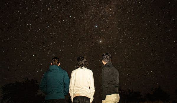 Três meninos observando o céu estrelado