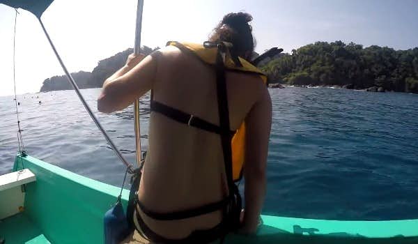 Mulher saltando do barco para a água da ilha de Cano