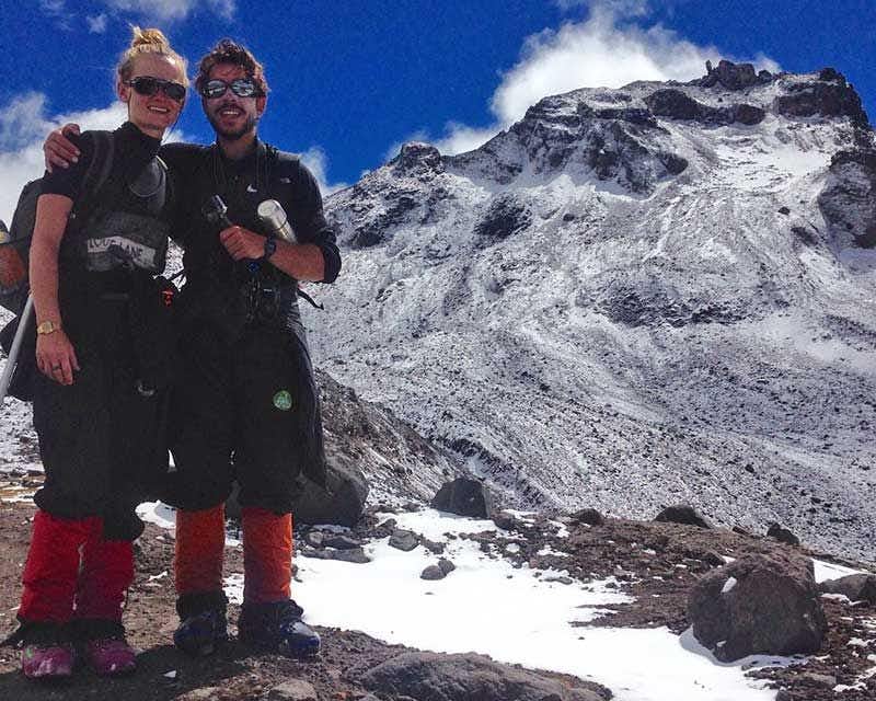 dois alpinistas felizes após chegarem ao cume de carihuairazo