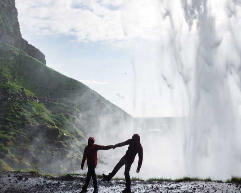 Viajantes sob a cachoeira Seljalandsfoss