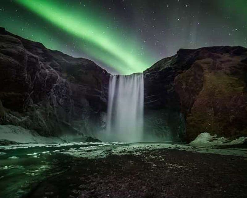 Cachoeira Skogafoss com a aurora boreal