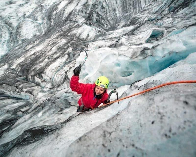 mulher escalando no gelo na geleira vatnajökull