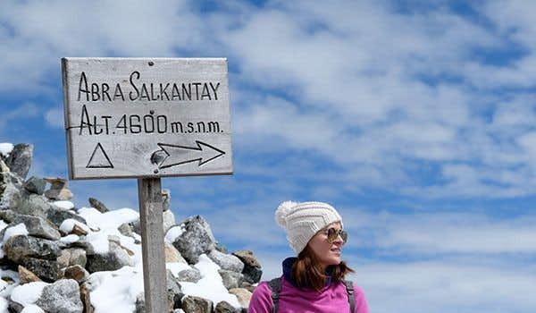 garota em frente à placa abra salkantay durante a trilha salkantay sky lodge