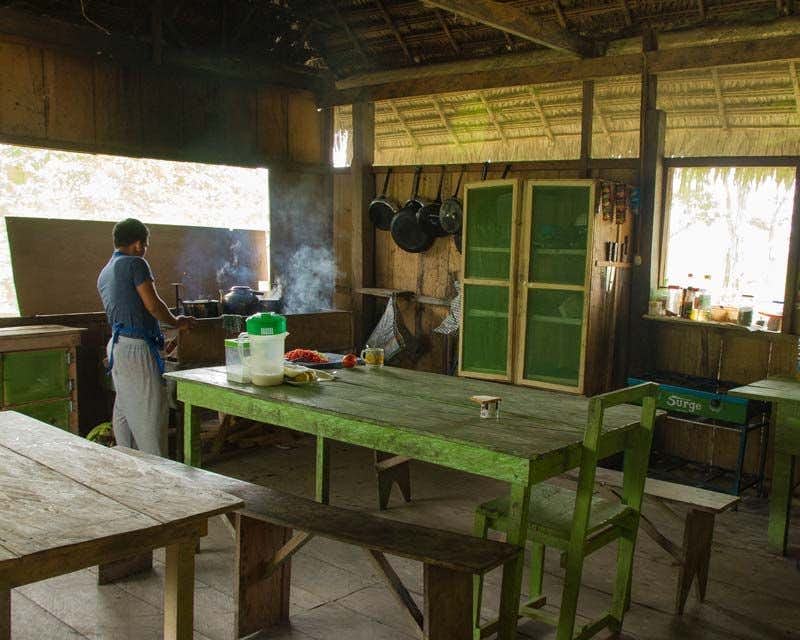 Cozinheiro trabalhando na cozinha da pousada privada para o passeio na selva de Iquitos