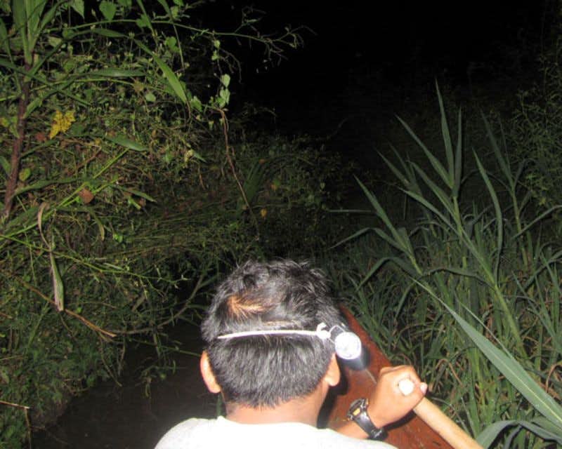 O homem navega de canoa à noite através do rio Amazonas na selva de Iquitos.