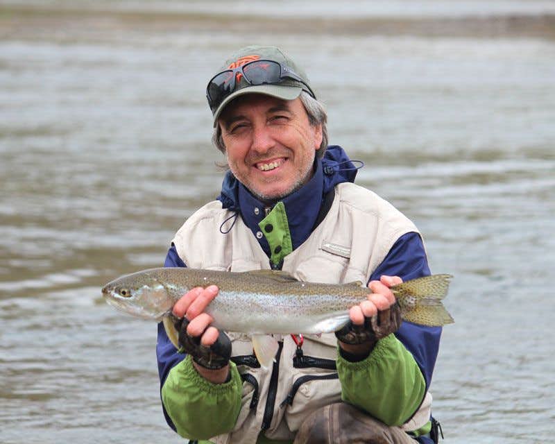 Ein Fischer hält eine Forelle in einem patagonischen Fluss
