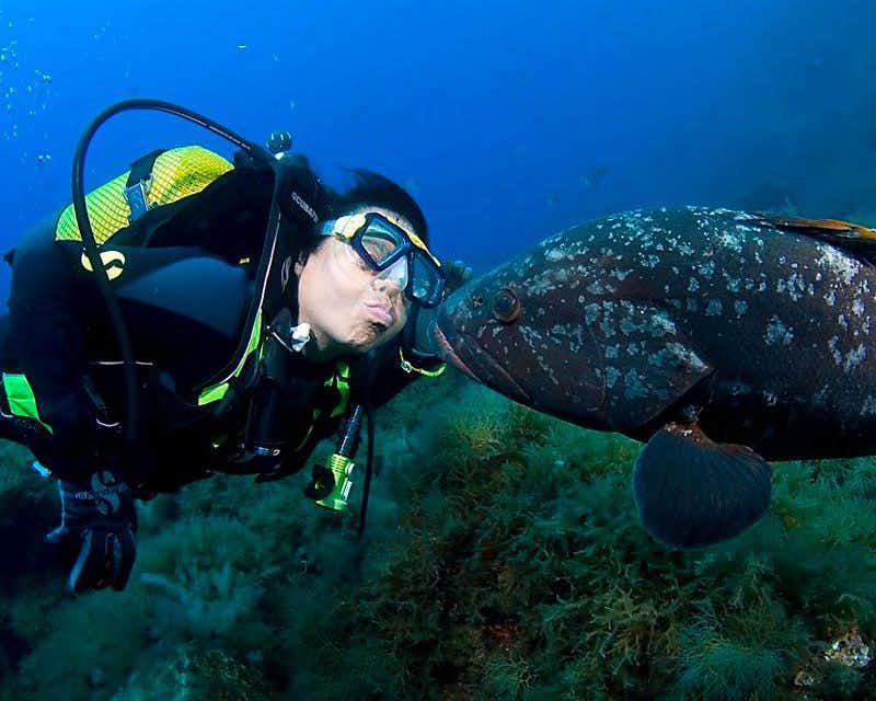 Mädchen küsst einen Fisch unter dem Meer in mallorca Spanien