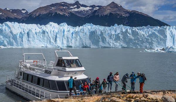 people disembarking with the perito moreno in the background