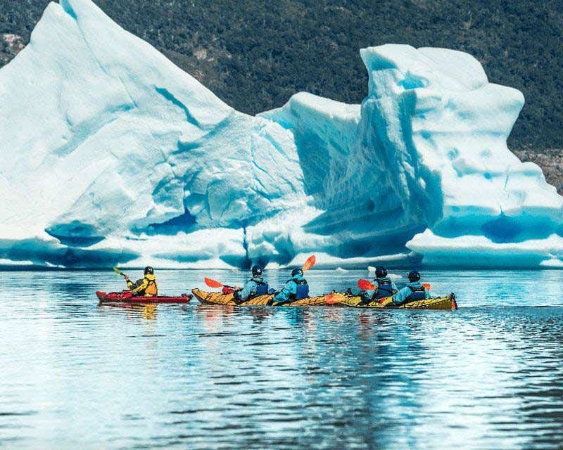 kayak group beside an iceberg