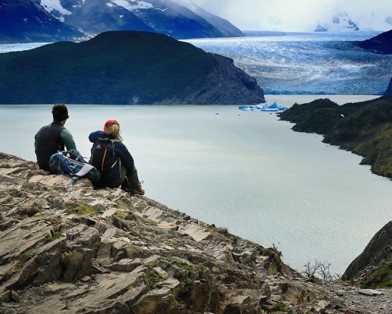 Hikers observing lake and glacier Grey