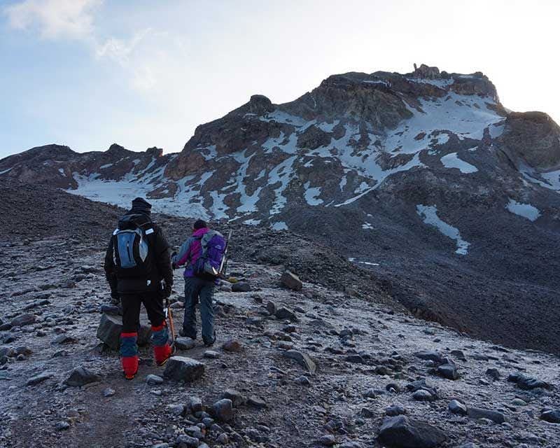 two mountaineers with their backs to the climb to carihuairazo