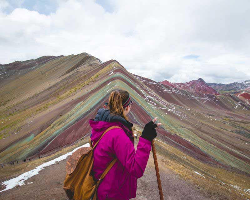girl on her back in front of rainbow mountain in peru
