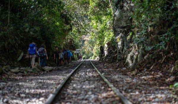 people walking along the train tracks linking hidroelectrica with aguas calientes