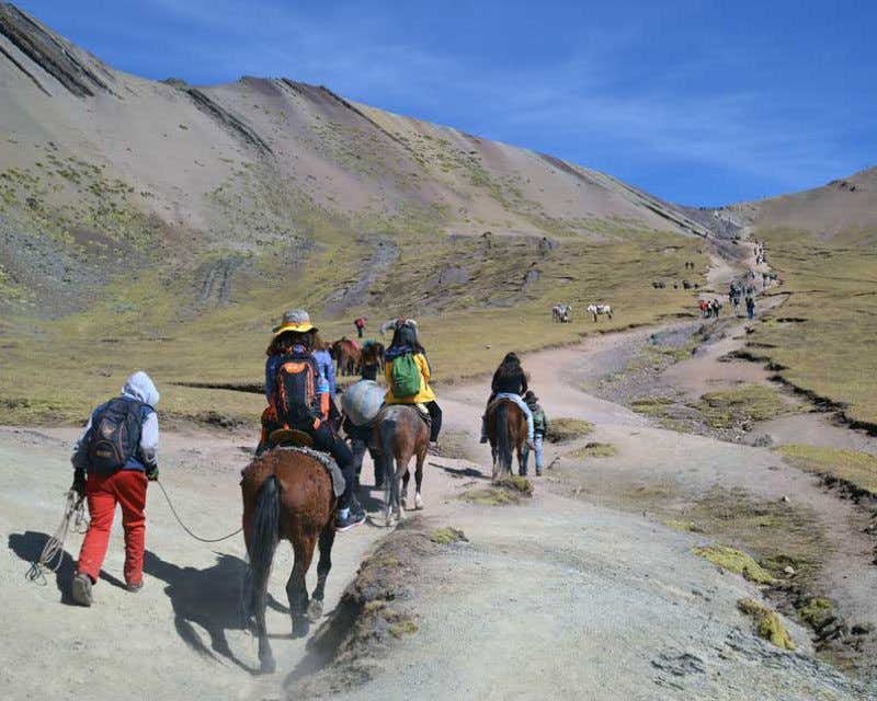 Travelers horseback riding to Vinicunca