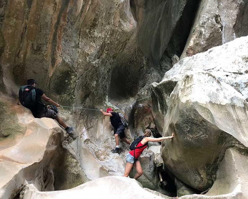 three people descending the torrent with the help of a rope