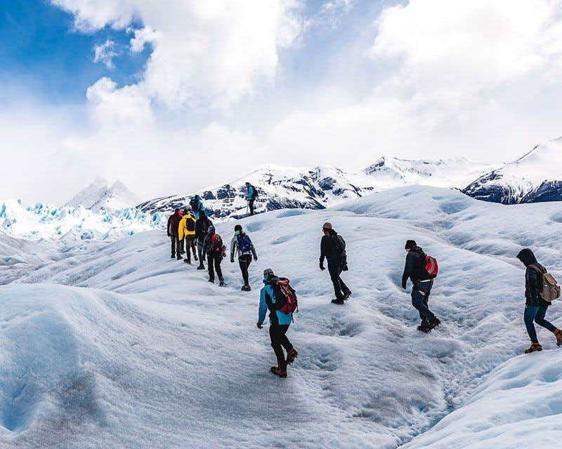 personas en lo alto de una montaña de hielo en el minitrekking perito moreno