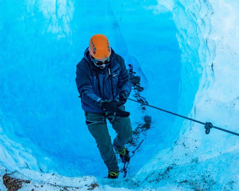 chico escalando por un tunel del glaciar grey