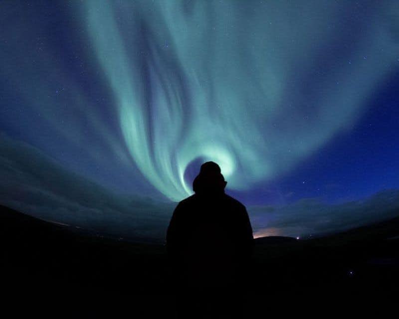 viajero observando aurora boreal azul
