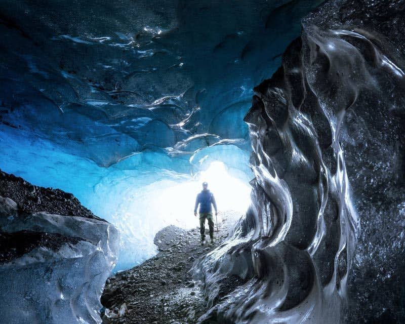 Viajero entrando en la cueva de hielo azul