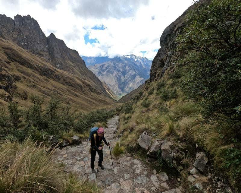 chica subiendo escaleras del camino inca con palos de trekking