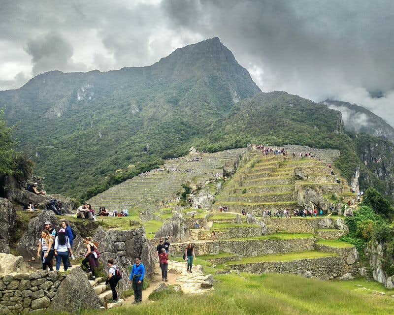 turistas visitando machu picchu en un dia nublado