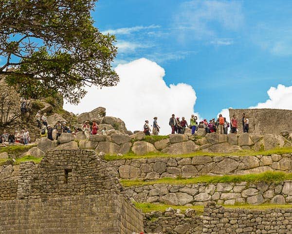 Grupo de turistas recorriendo las murallas de una fortaleza inca
