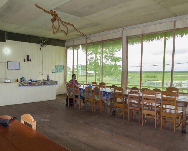 Aventurero sentado en la mesa del comedor del lodge en la selva de iquitos tour