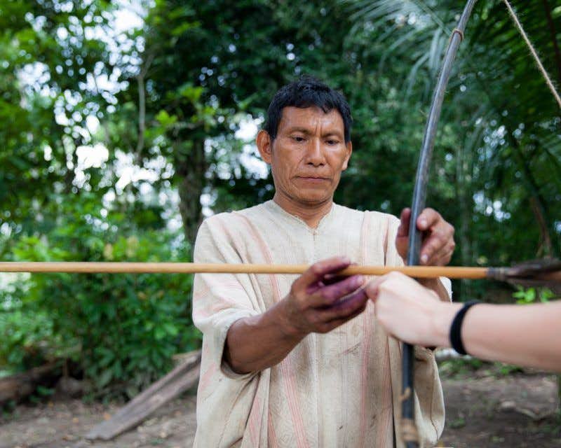 nativo enseñando a tirar con arco en el campamento shiringuero
