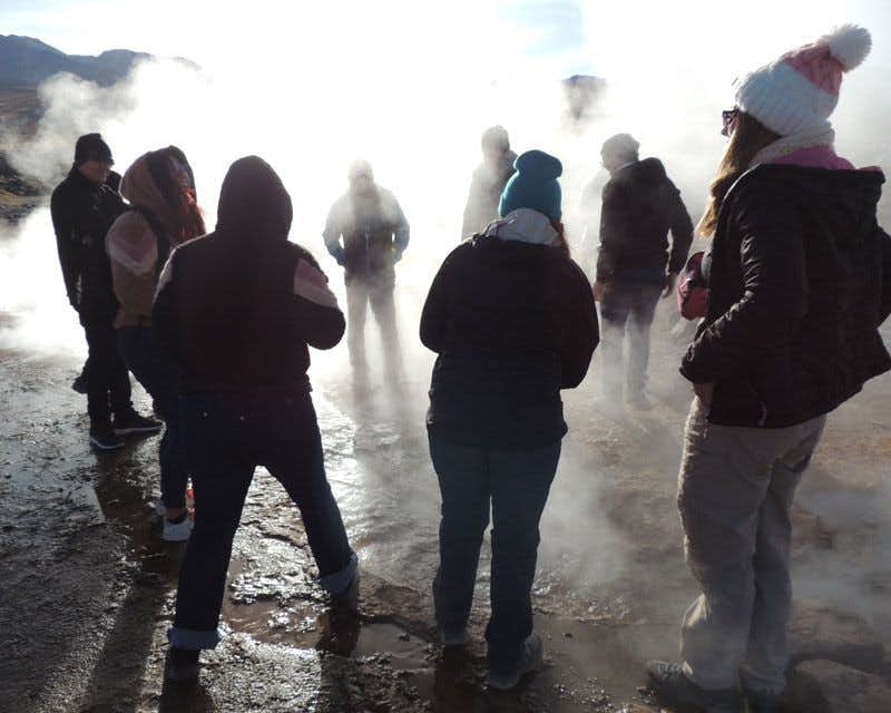guide expliquant les geysers et groupe de personnes à côté du vapeur