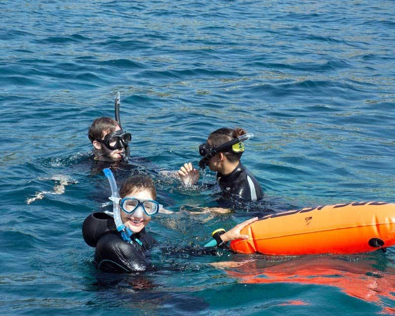 trois personnes faisant de l'apnée dans la mer avec des combinaisons de plongée