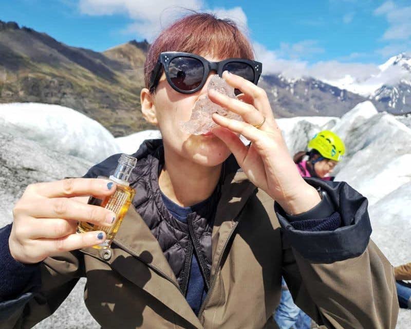 fille buvant du whisky dans la glace d'un glacier
