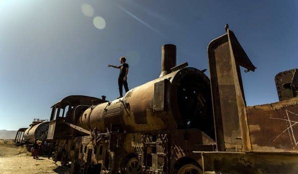 Viaggiatore al cimitero dei treni nella piana di sale di Uyuni