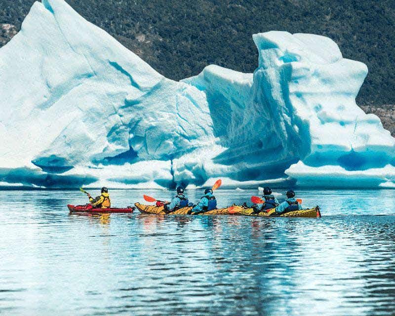 gruppo di kayak accanto a un iceberg