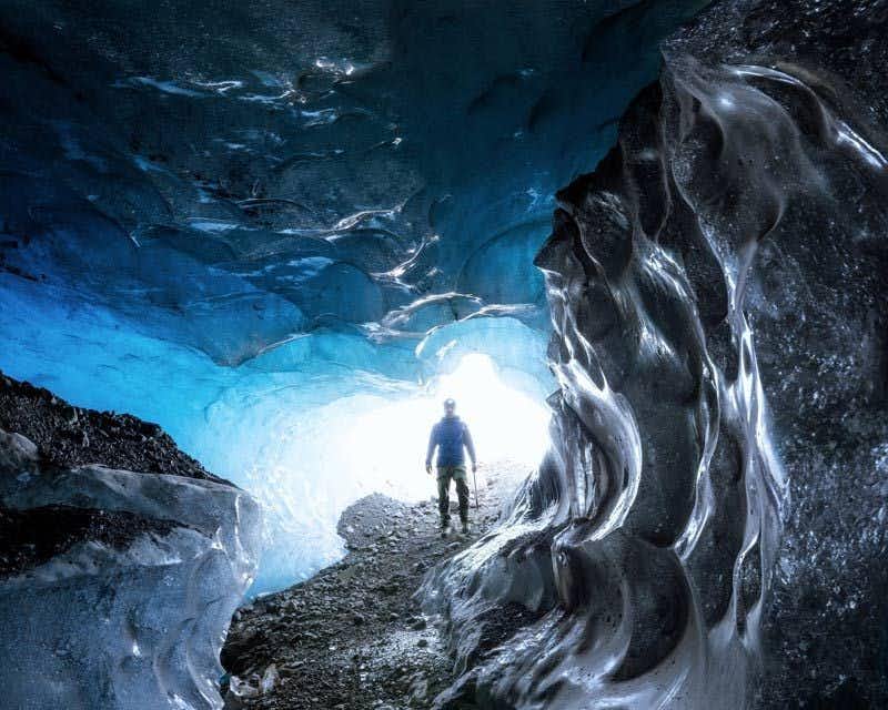 Viaggiatore che entra nella grotta di ghiaccio blu