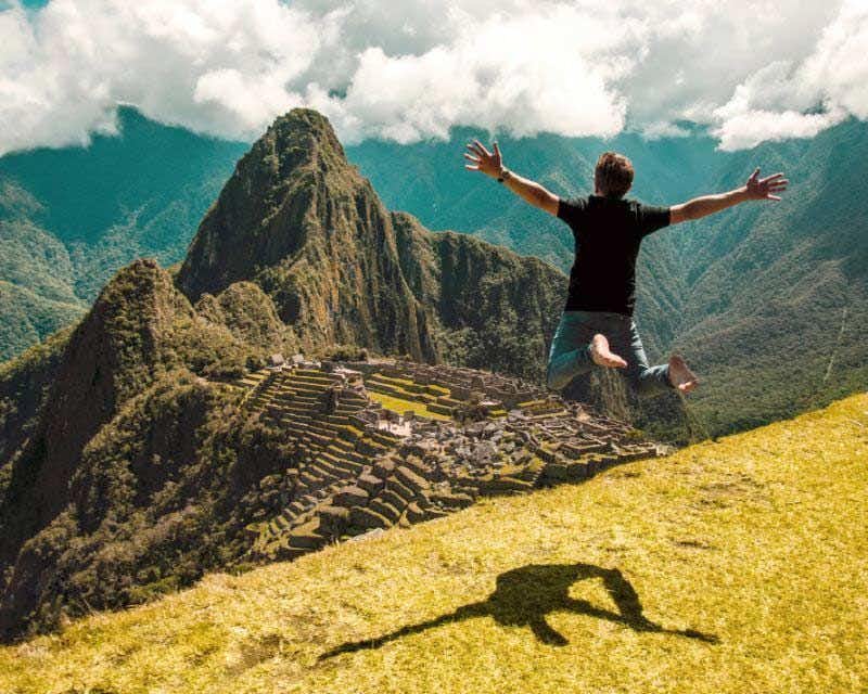Uomo che salta sul trekking di Salkantay con vista su Machu Picchu e Huayna Picchu
