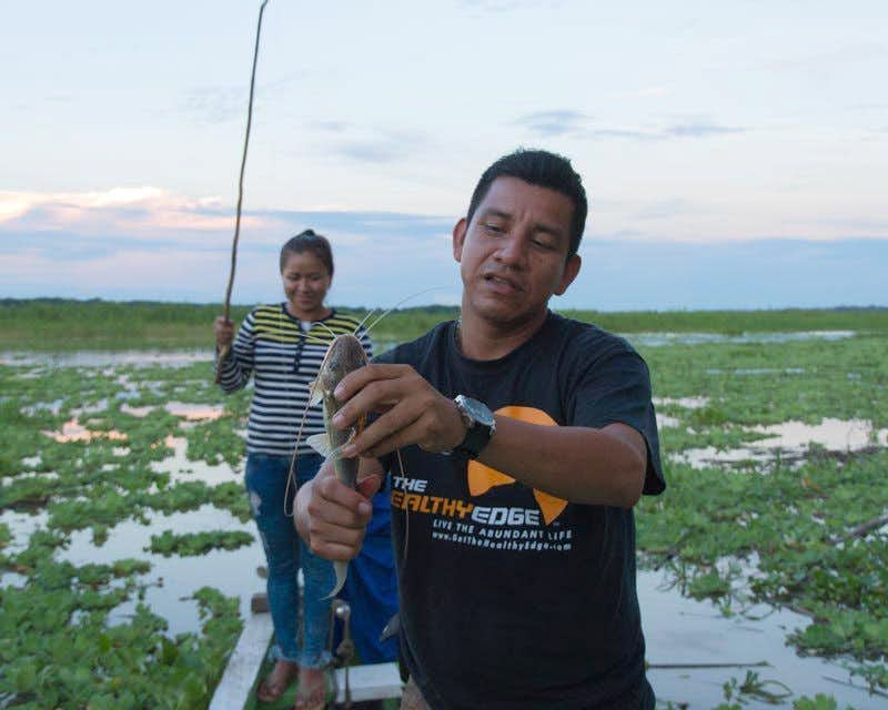 La guida mostra alla telecamera uno dei piranha pescati nella giungla di iquitos