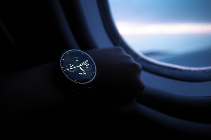 Reloj de mano cerca de la ventana del avión