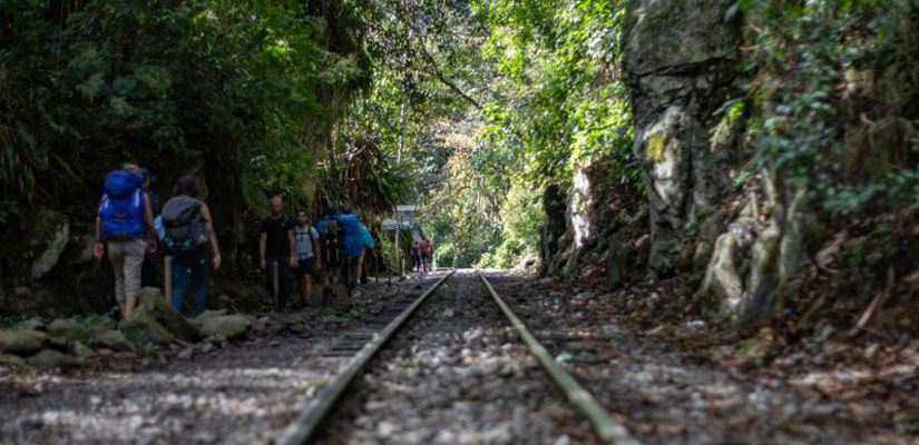 people walking along the railroad track in inca jungle