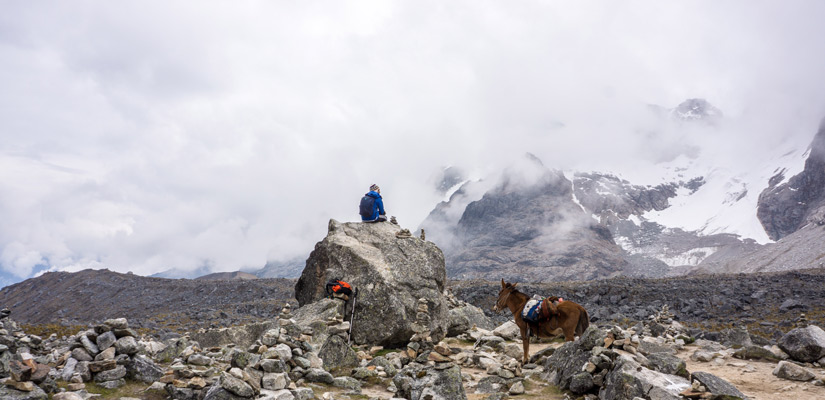 persona sentada en piedra y mula al lado en salkantay trek