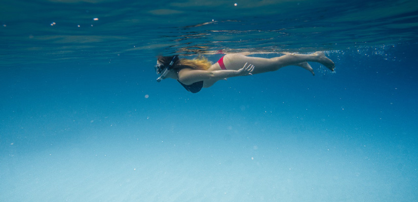 person with goggles and snorkel snorkeling