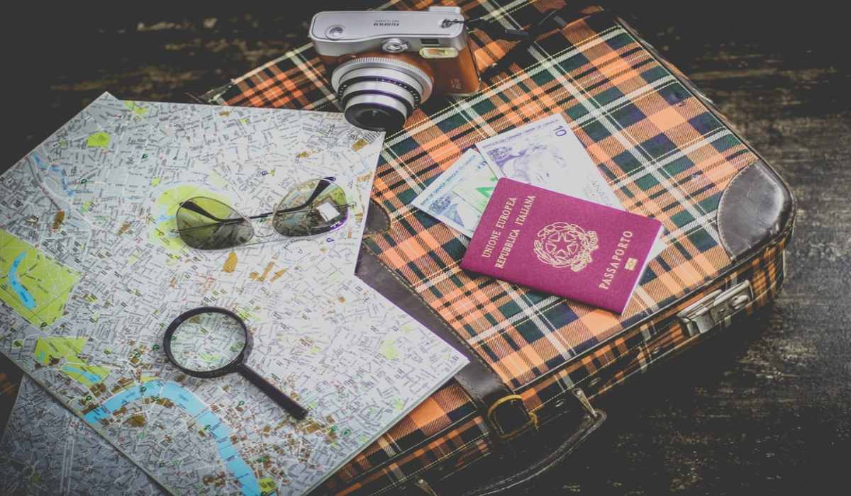 maleta, mapa, dinero, cámara y gafas de sol